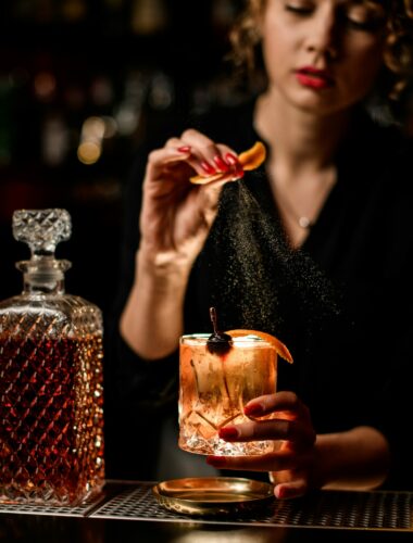 Young,Woman,Bartender,Holds,Glass,Of,Cold,Alcohol,Cocktail,In
